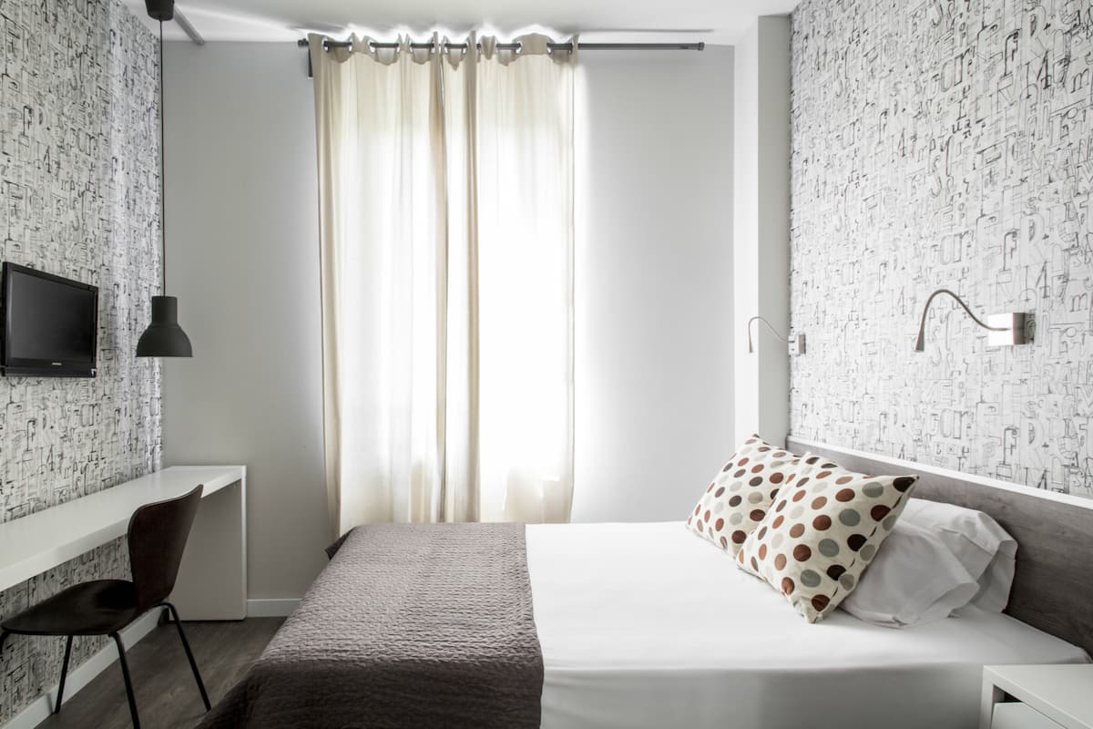 Een moderne slaapkamer met een bed, een bureau en een televisie.
