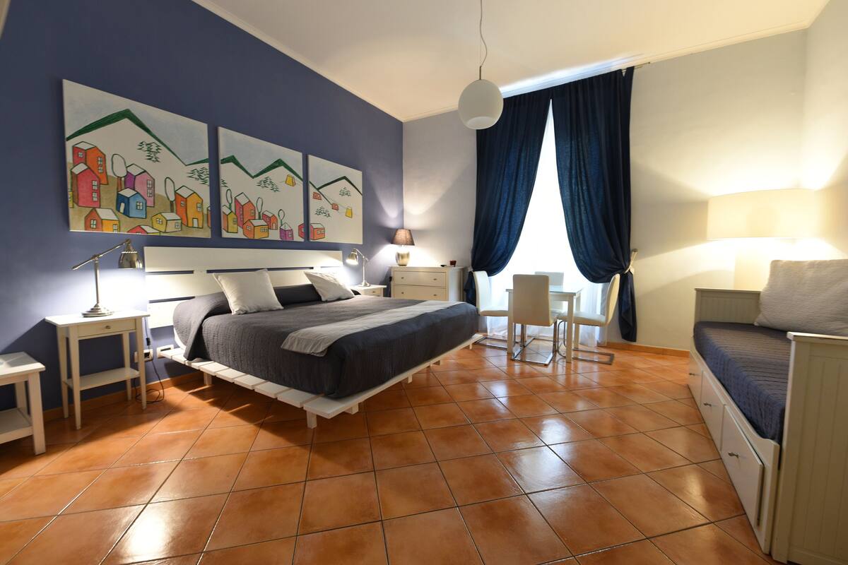 A bedroom with a bed, bedside tables, a desk, and a chair.