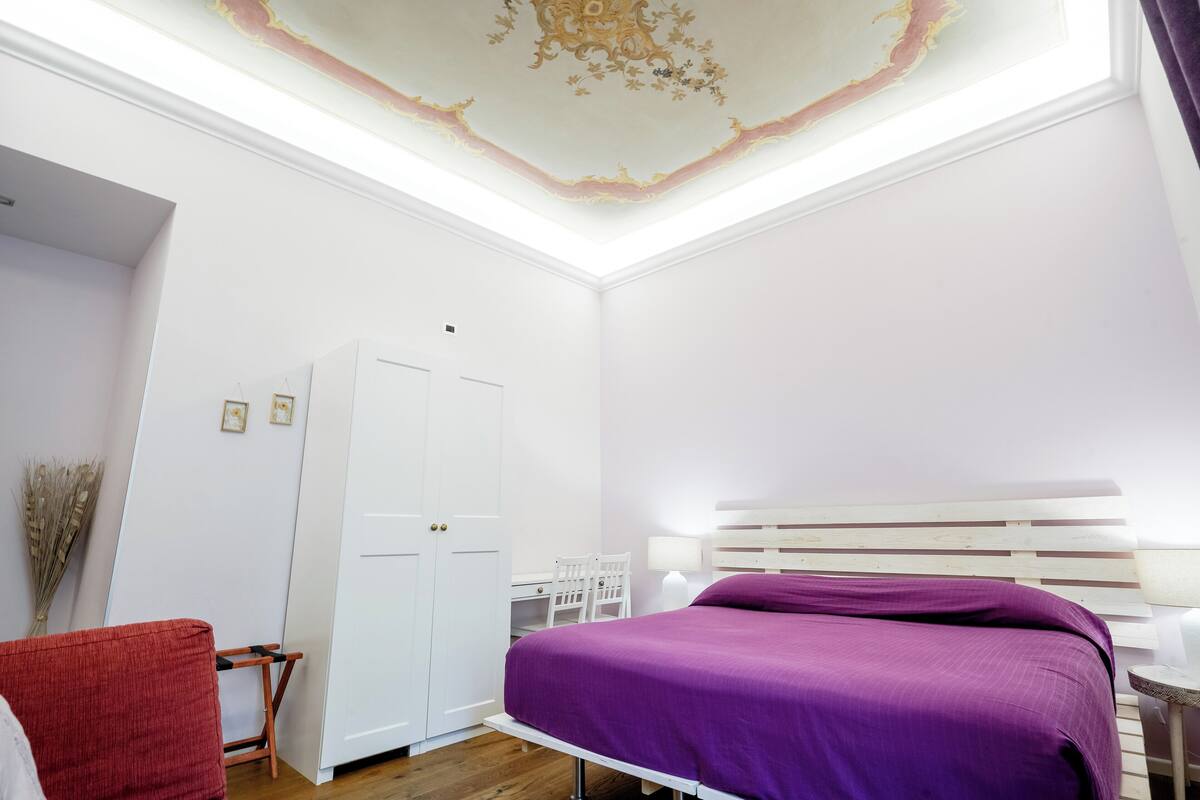 A bedroom with a bed, a desk, a chair, and a wardrobe.
