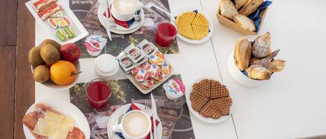 A table set with various food items, including bread, pastries, and fruit, along with cups of coffee and juice.