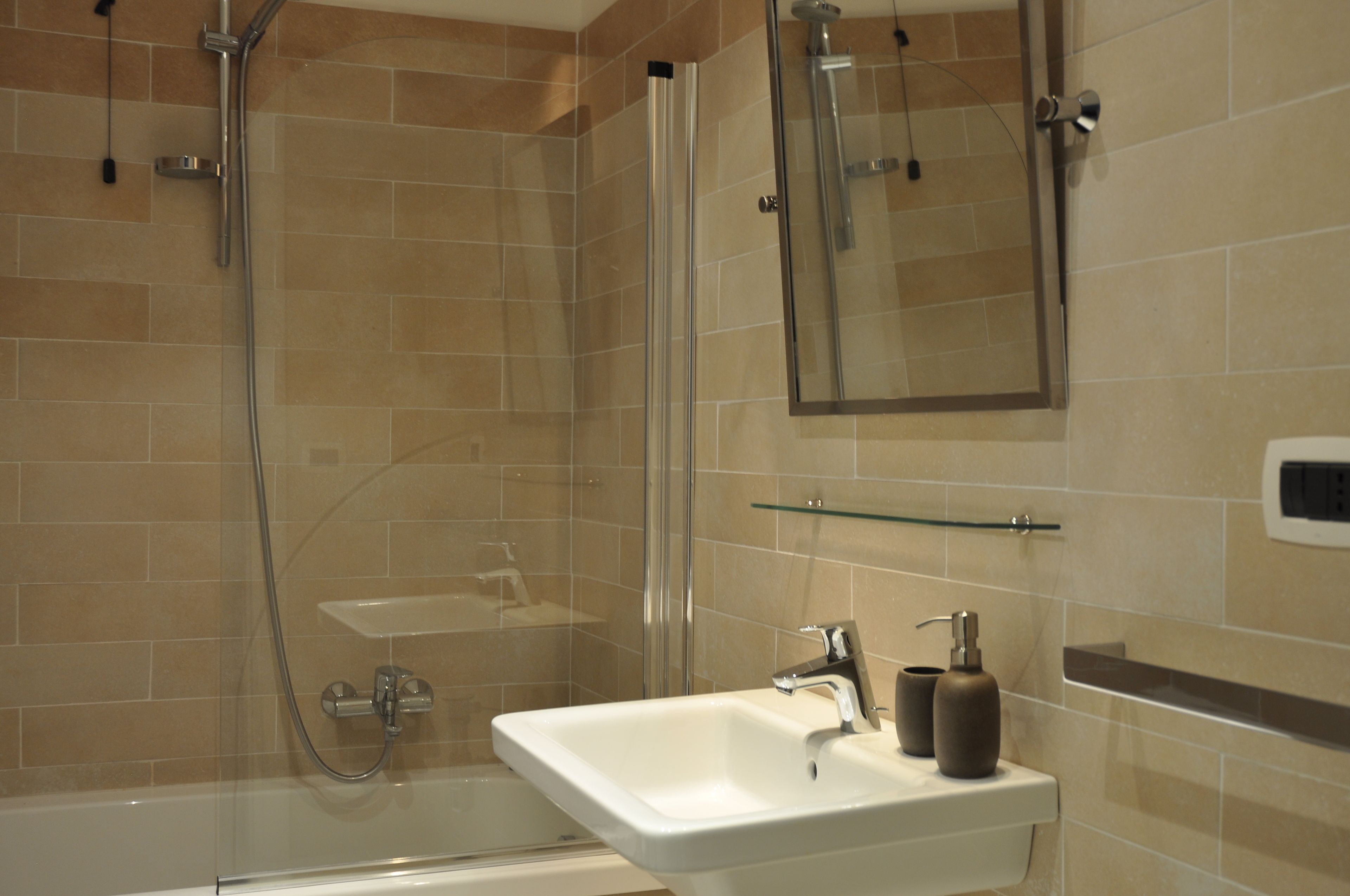 Une salle de bain moderne avec une douche à parois de verre, un lavabo blanc et un miroir au-dessus.