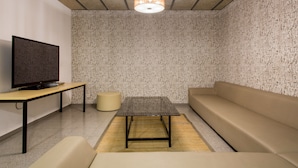 A modern living room with a television, sofa, and a table. - Residencia Universitaria Resa Campus de Montilivi (Girona)