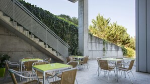 An outdoor patio with tables and chairs, a concrete staircase, and a wall with greenery. - Residencia Universitaria Resa Campus de Montilivi (Girona)