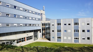 A modern building with multiple floors, large windows, and a central staircase. - Residencia Universitaria Resa Campus de Montilivi (Girona)