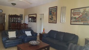 A living room with two black leather sofas, a coffee table, and a dining area with wooden furniture. - Ocho Rios Almond Tree Villas (Ocho Rios)