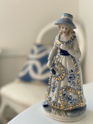 A ceramic figurine of a woman in a blue dress with gold accents, placed on a white surface. - Hotel Hamngatan 27 (Falkenberg)