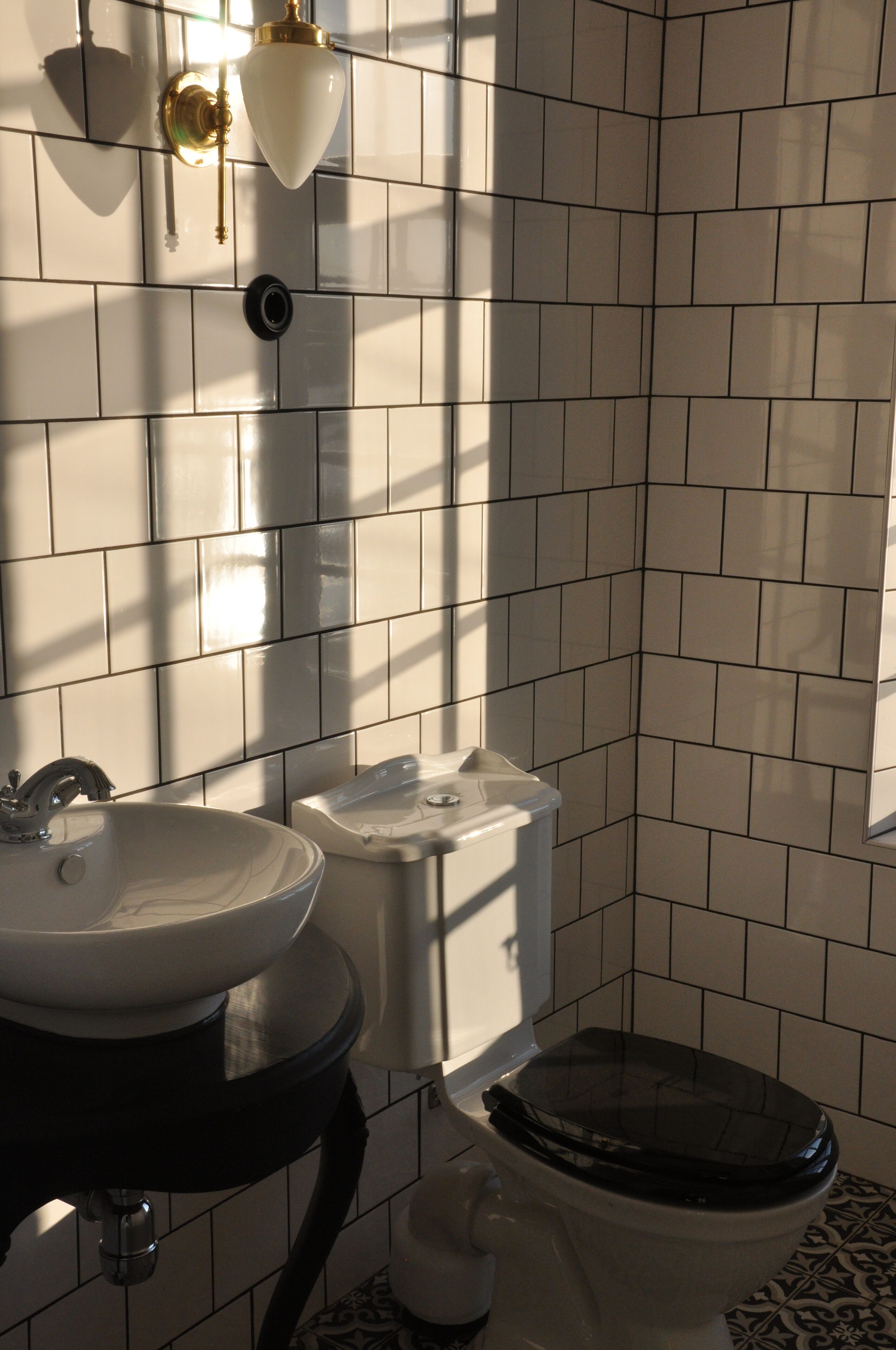 A bathroom with a sink, toilet, and wall-mounted light fixture.