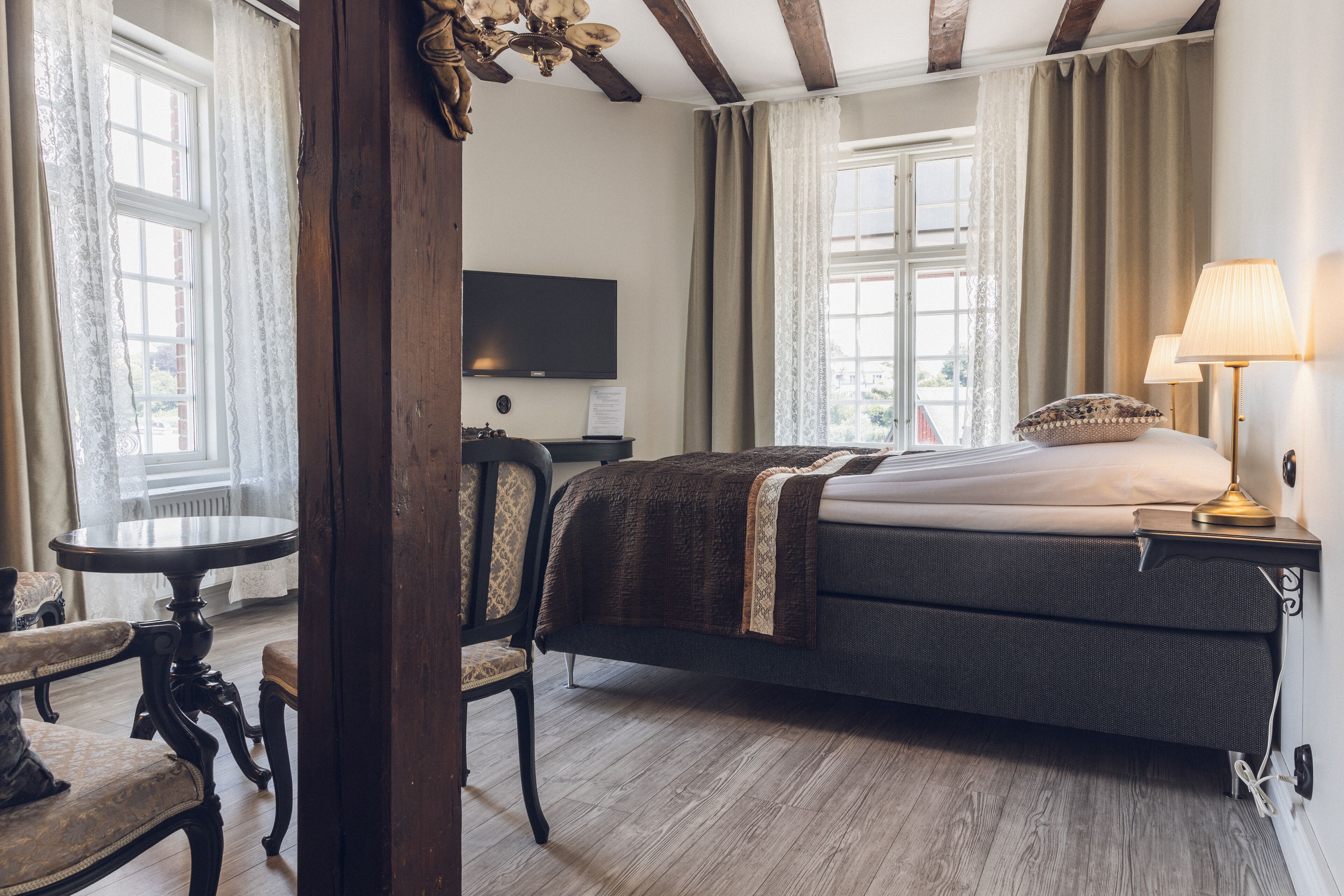 A hotel room with a bed, a television, a table, and a chair.