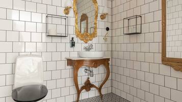 A bathroom with white tiled walls, a white sink, a gold-framed mirror, and a black toilet.