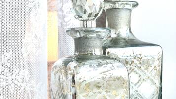 Deux carafes en verre, dont le sommet est taillé à facettes comme un diamant, posées sur une surface réfléchissante.