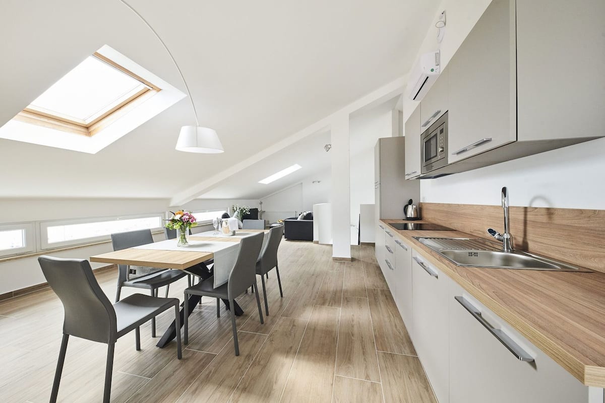 A modern kitchen with skylights, a dining area with chairs, and a view of the city.