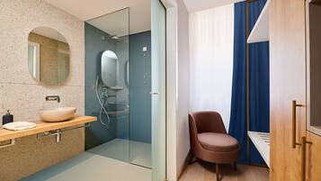 A modern bathroom with a glass shower enclosure, a round mirror, and a wooden vanity.