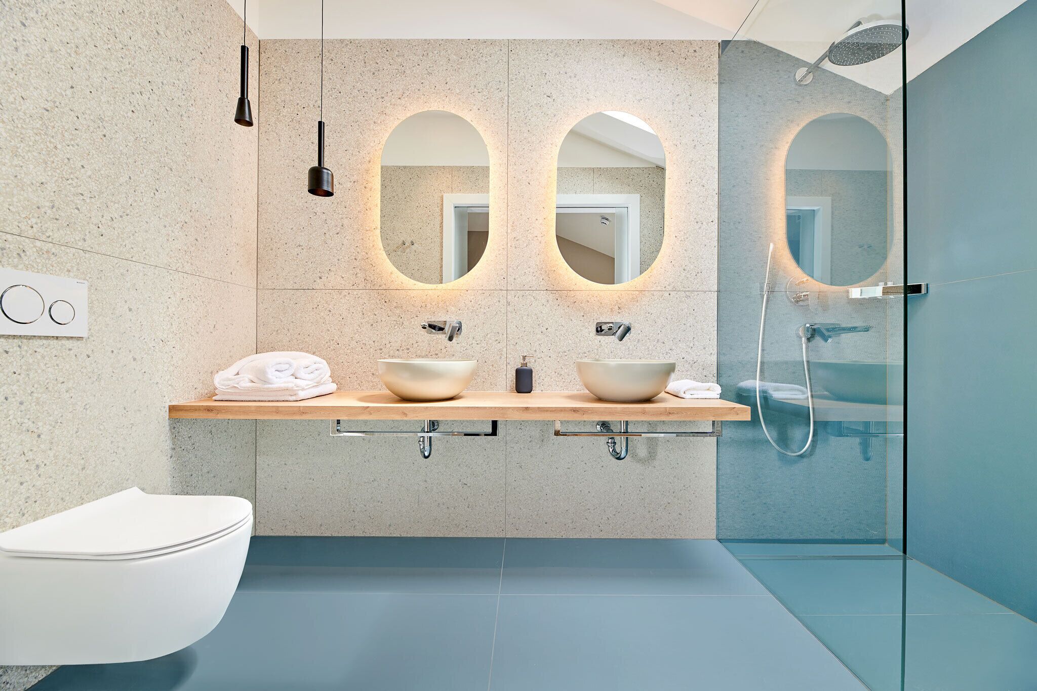 Un bagno moderno con due lavandini, un water e una doccia.