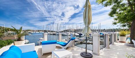 A terrace with white wicker furniture, blue cushions, and a table.