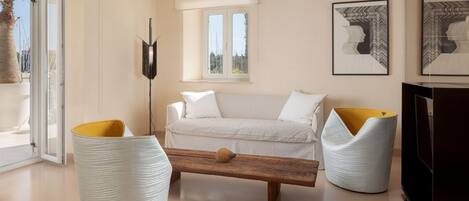 A modern living room with a sofa, two white chairs, a wooden coffee table, and a television.
