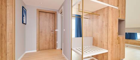 A modern room with wooden flooring, a white bed, and a wardrobe with gold handles.