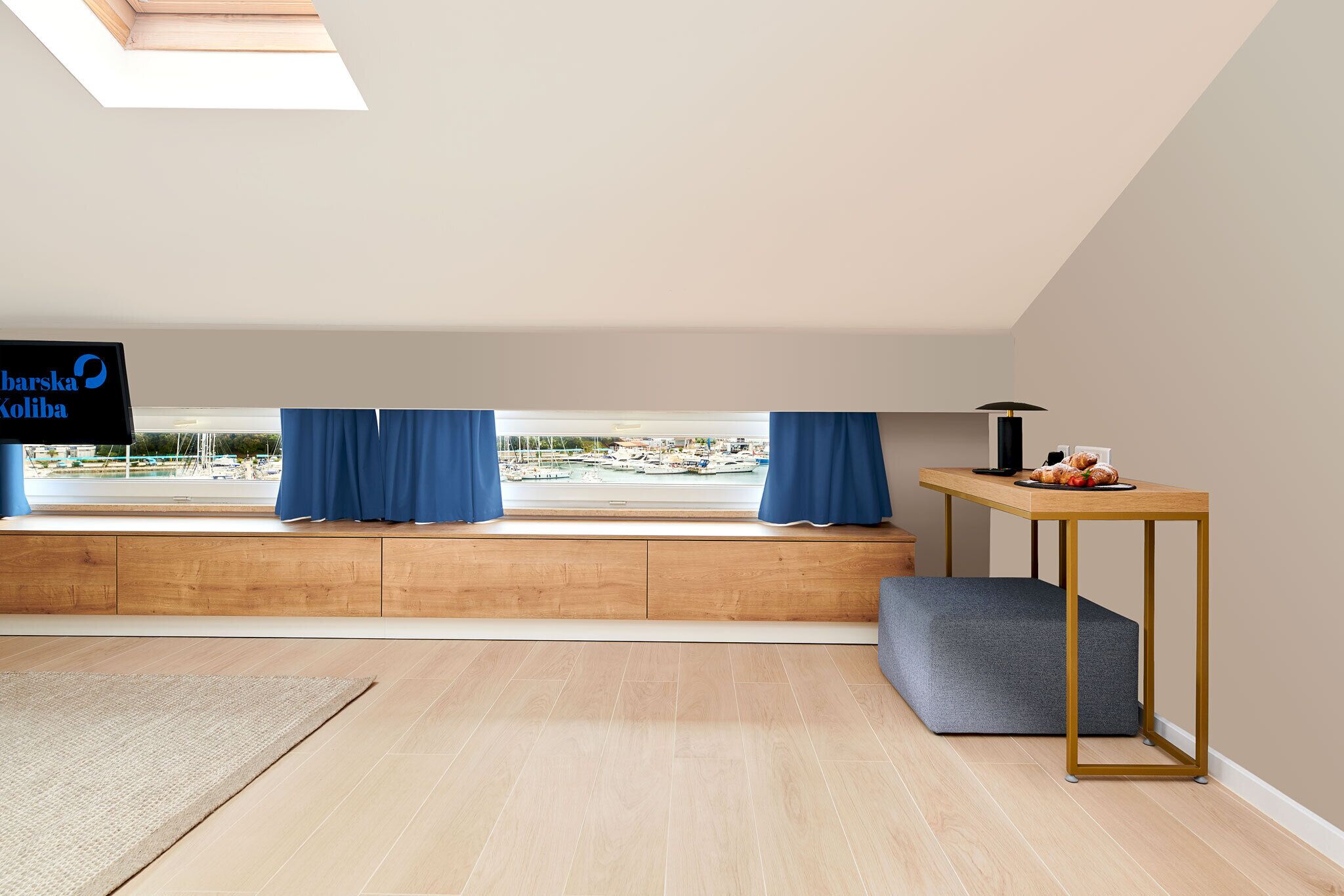 Una habitación moderna con un banco de madera, una mesita con una lámpara y un televisor en la pared.