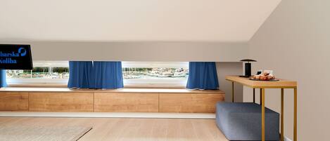 Una habitación moderna con un banco de madera, una mesita con una lámpara y un televisor en la pared.