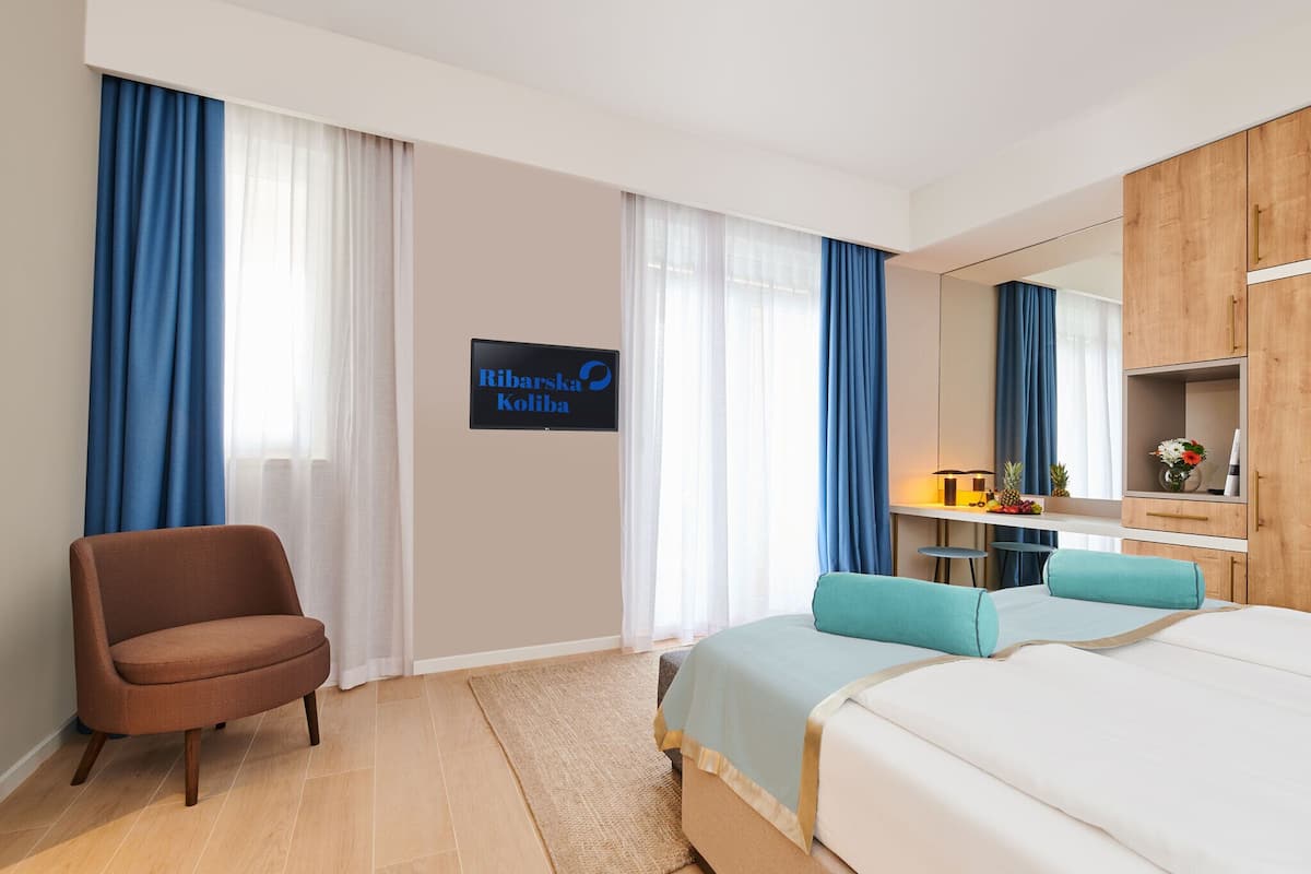 A hotel room with a bed, a chair, a desk, and a mirror.