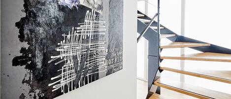 A modern staircase with wooden steps and metal railings, leading to an upper floor.