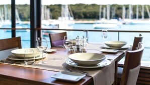 A dining table set for four with a view of a marina and boats in the background. - Ribarska Koliba Resort (Pula)