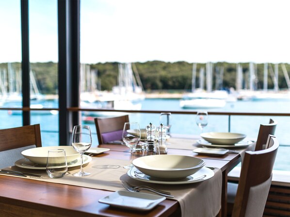 A dining table set for four with a view of a marina and boats in the background.