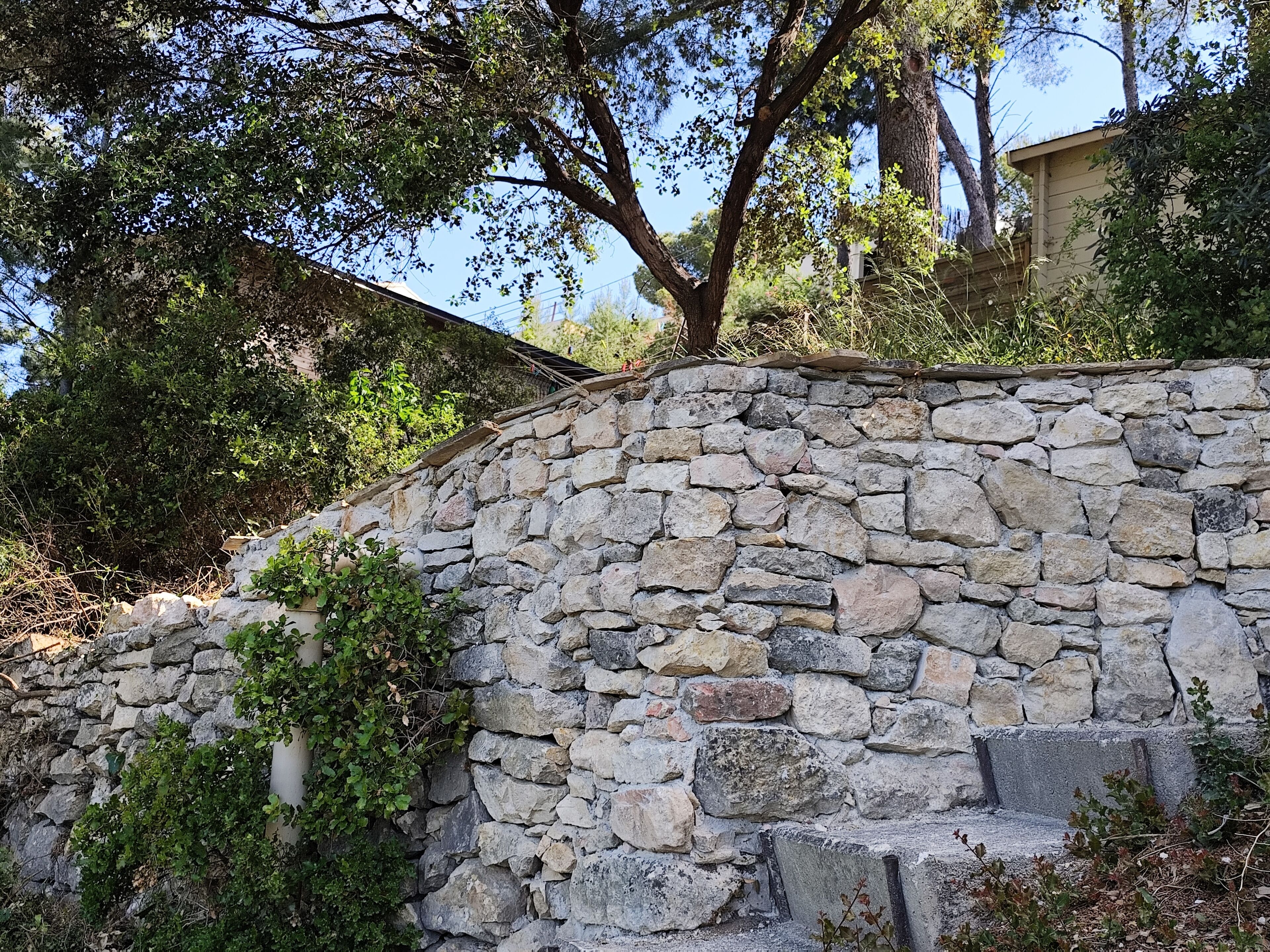 A stone wall with steps leading up to a building.