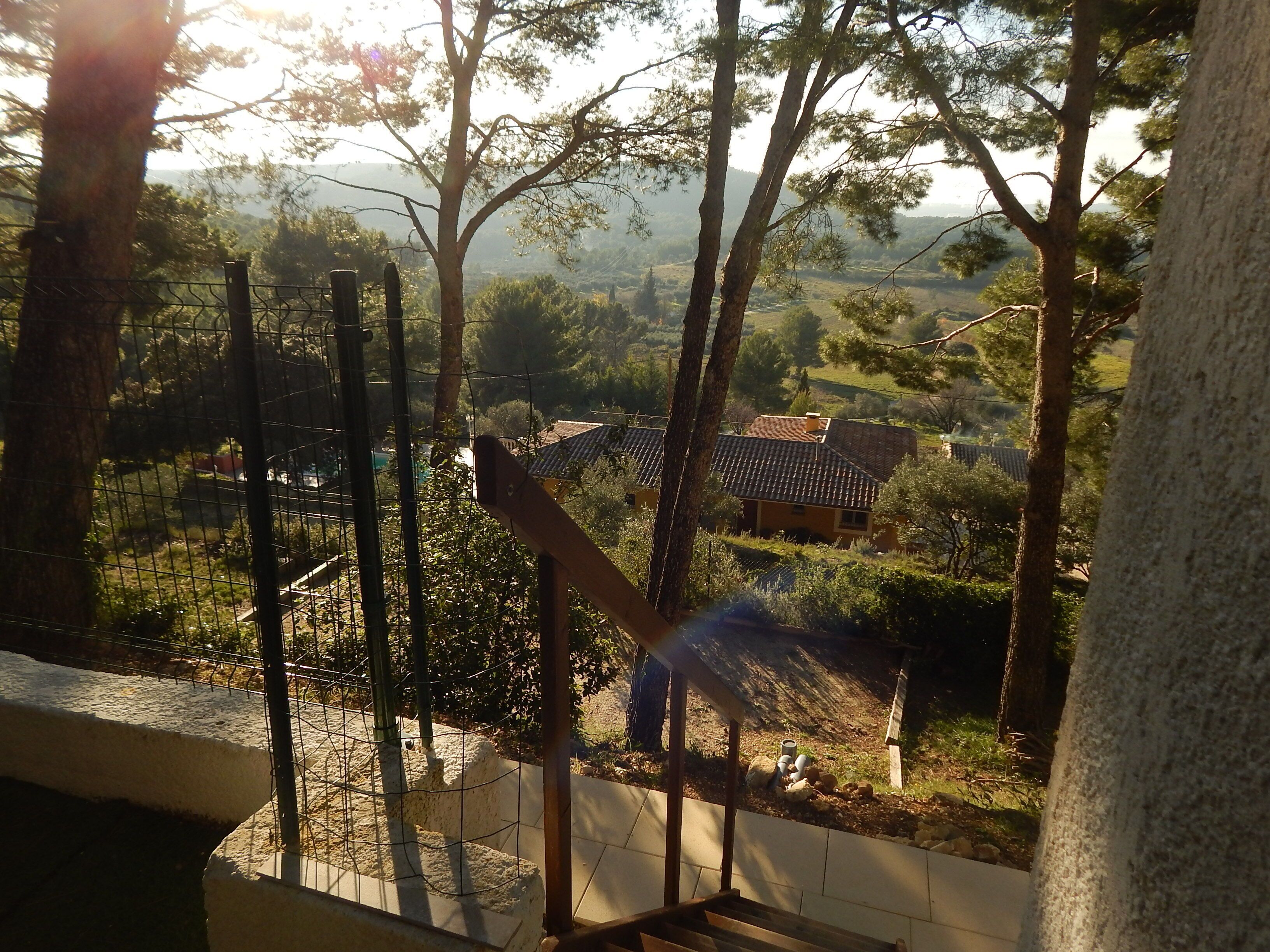 A view from a balcony overlooking a rural landscape with trees and houses.