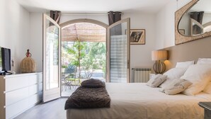 A bedroom with a bed, a television, a dresser, and a large window. - Le Mas des Roches (Velaux)