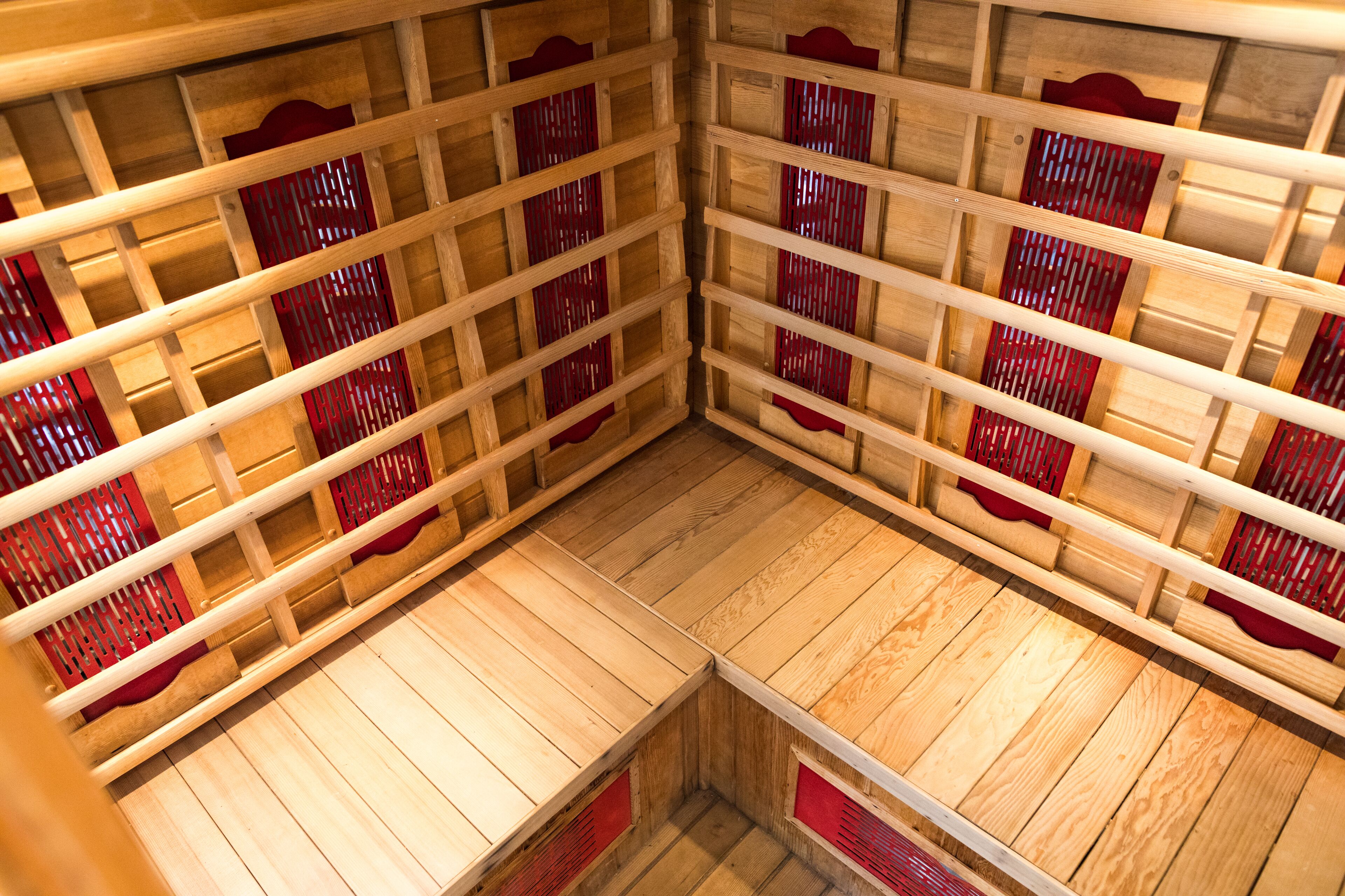 A sauna with wooden benches and red partitions.