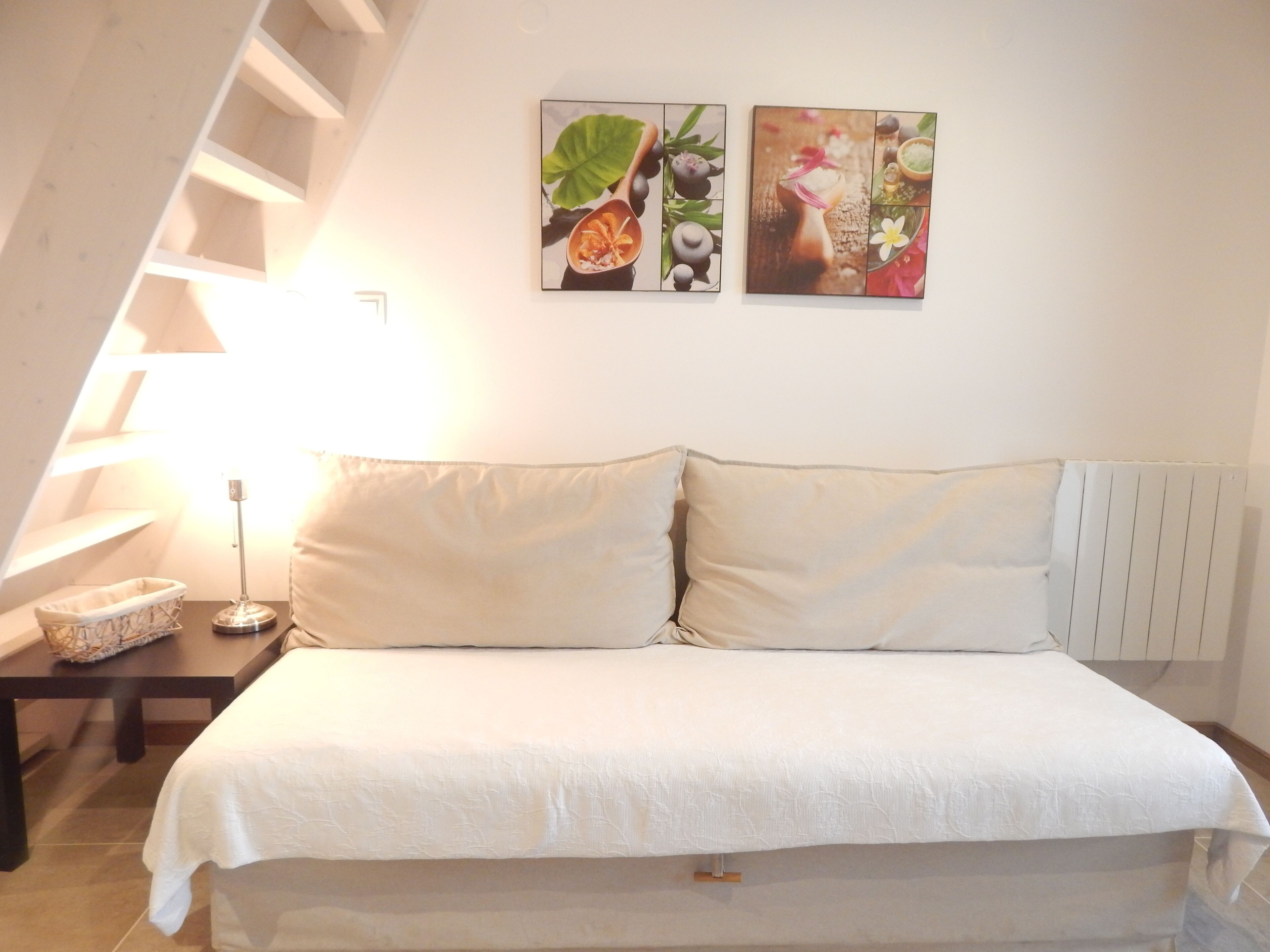 Une chambre à coucher avec un lit, une table de chevet et deux tableaux accrochés au mur.