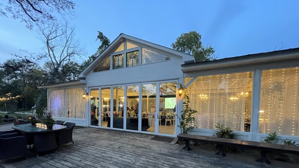 Ein modernes Gebäude mit großen Glasfenstern, einer Holzterrasse und Sitzgelegenheiten im Freien.