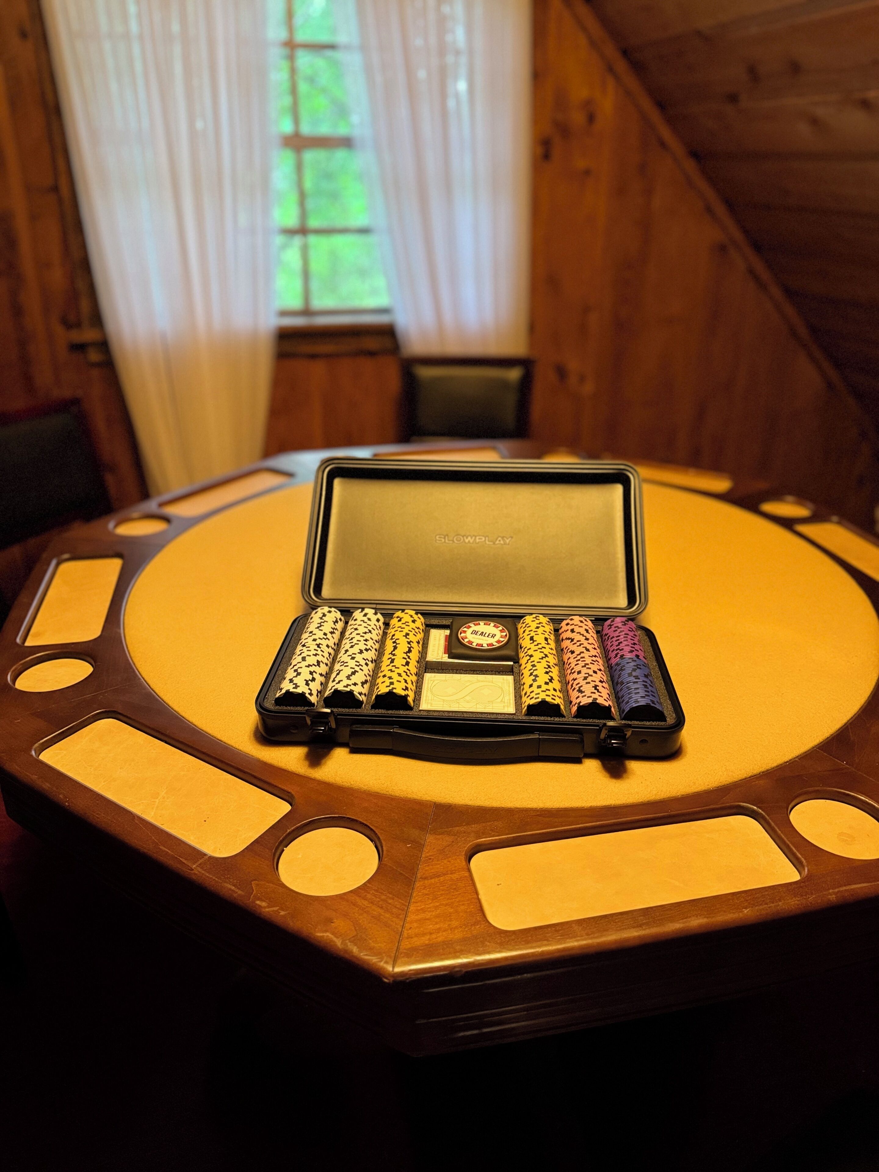 A table with a laptop and a set of colorful dice in a wooden room.