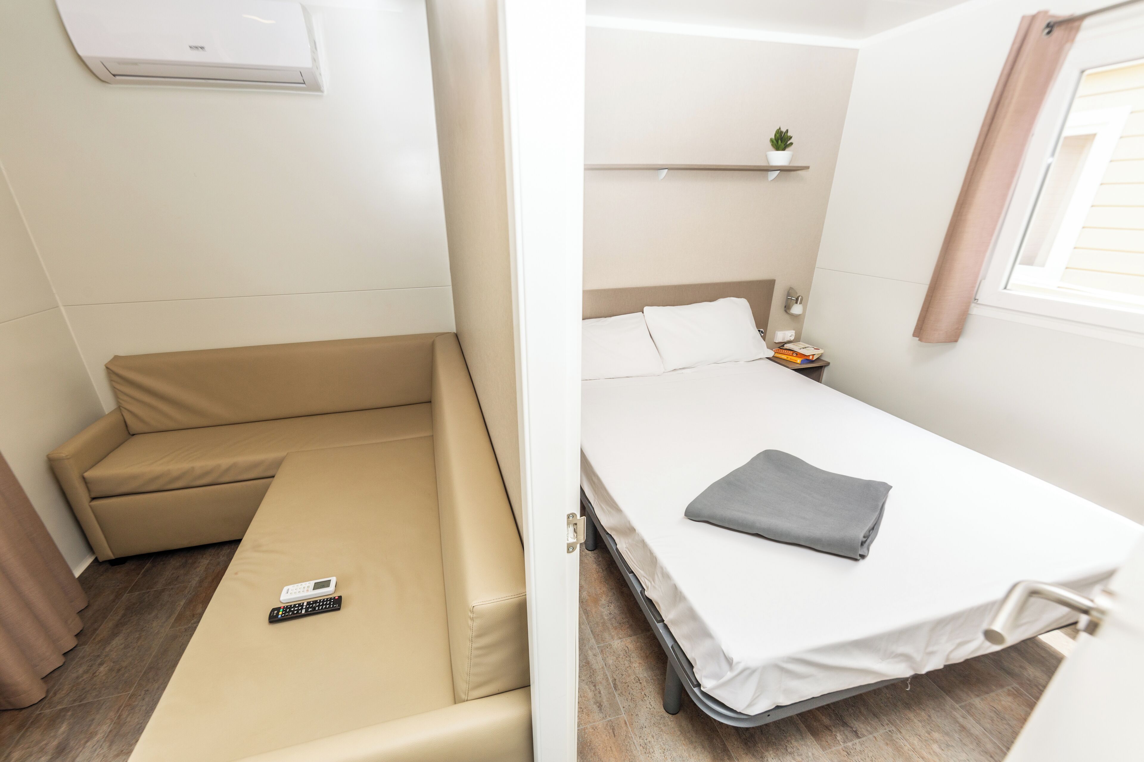 A compact room with a sofa bed and a single bed.