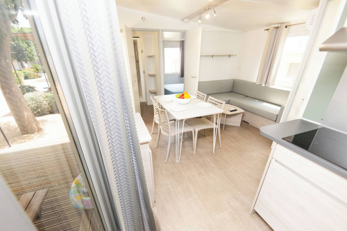 A modern kitchen with white cabinets, a built-in oven, and a dining area with a table and chairs.