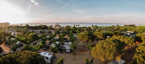 A campsite with RVs and tents, surrounded by trees and a beach view. - Camping Bellsol (Pineda de Mar)