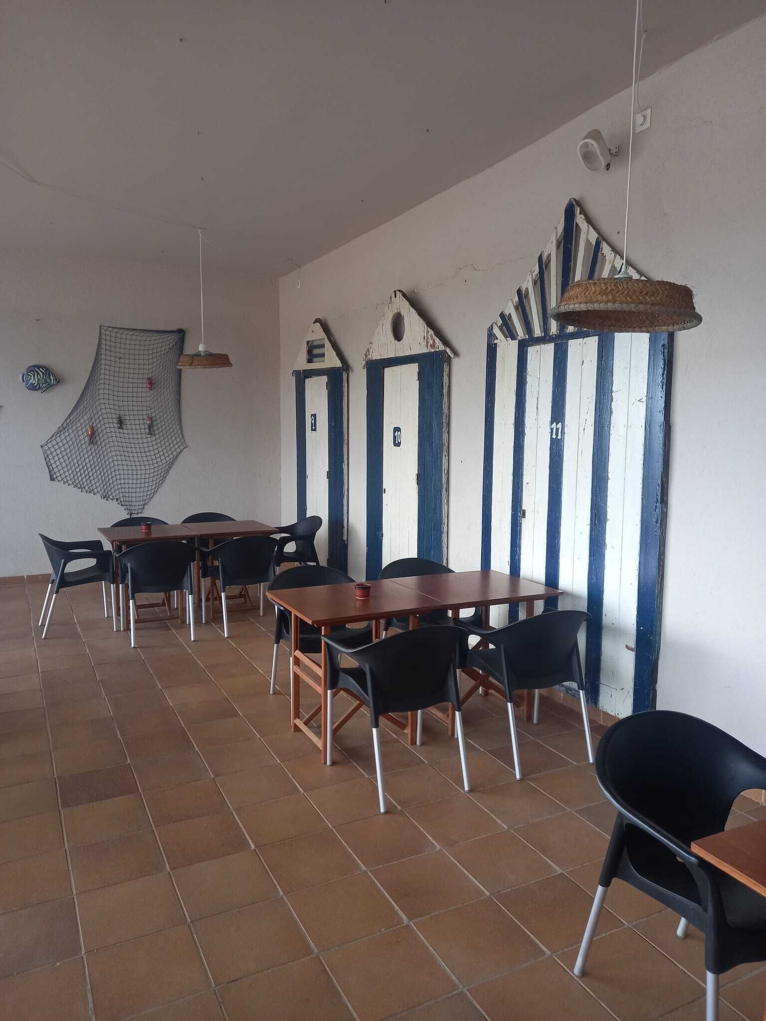 Et spiseområde med borde og stole, et vægophæng med mønster samt en loftlampe.