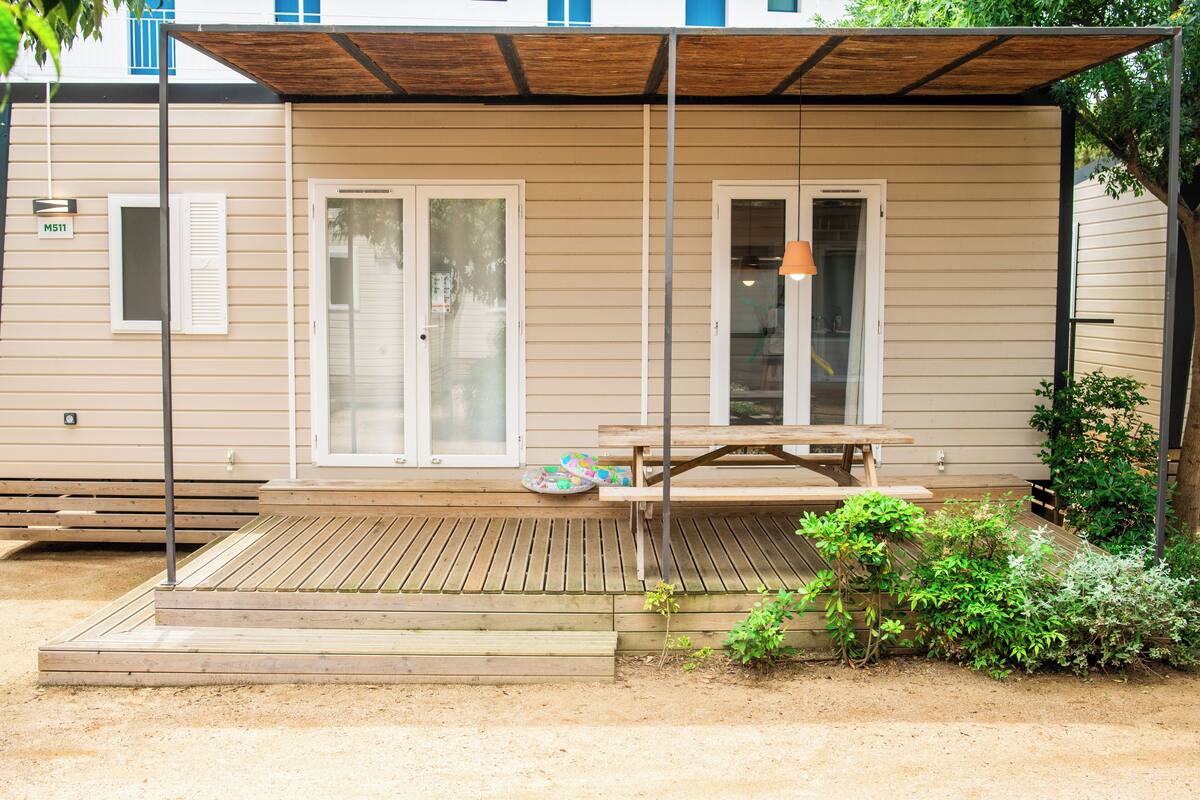 A covered outdoor area with a wooden deck, a bench, and a table.