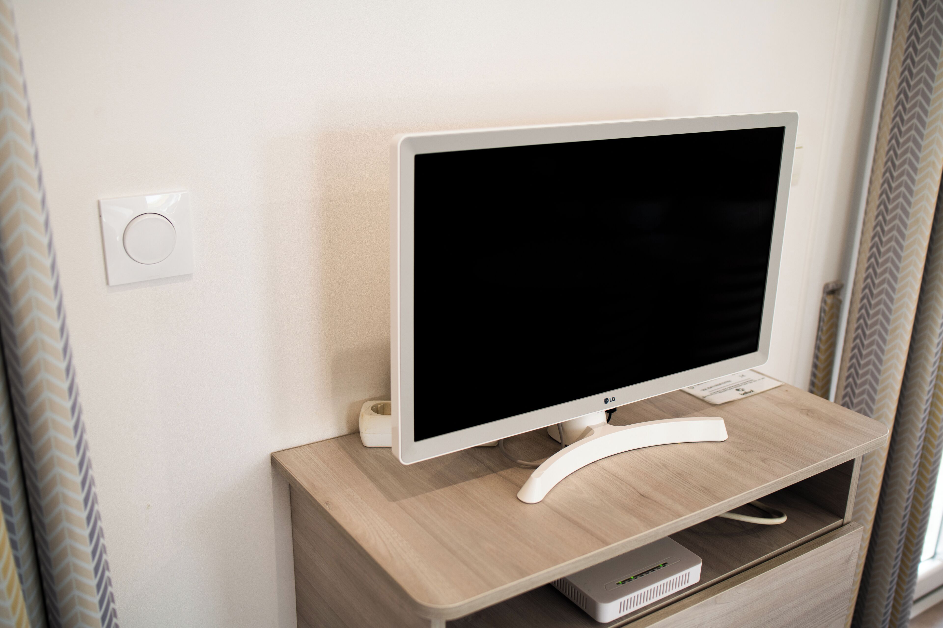 A modern room with a flat-screen TV on a wooden stand, a power outlet, and a cable management box.