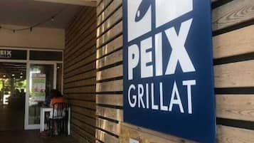 Un letrero que dice 'EL PEIX GRILLAT' en una pared de madera.