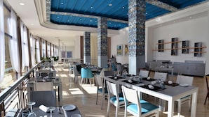 Un restaurant moderne avec de hauts plafonds, des colonnes décorées et une grande salle à manger dotée de tables et de chaises.