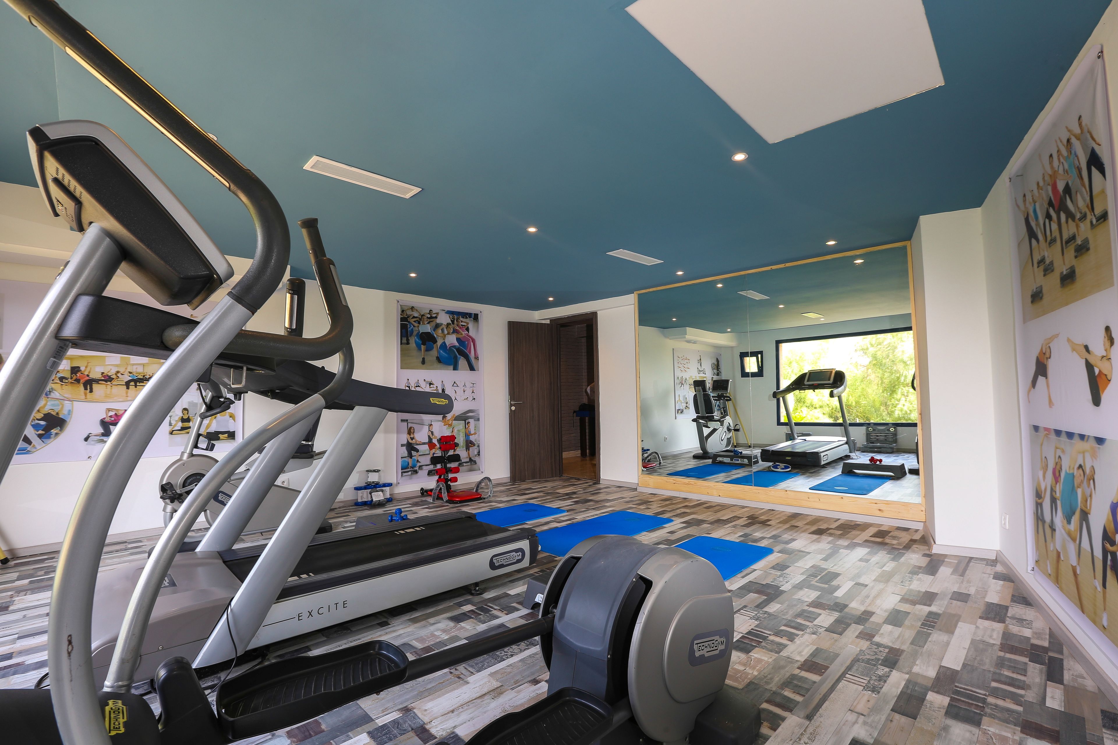 A gym with treadmills, stationary bikes, and exercise mats.