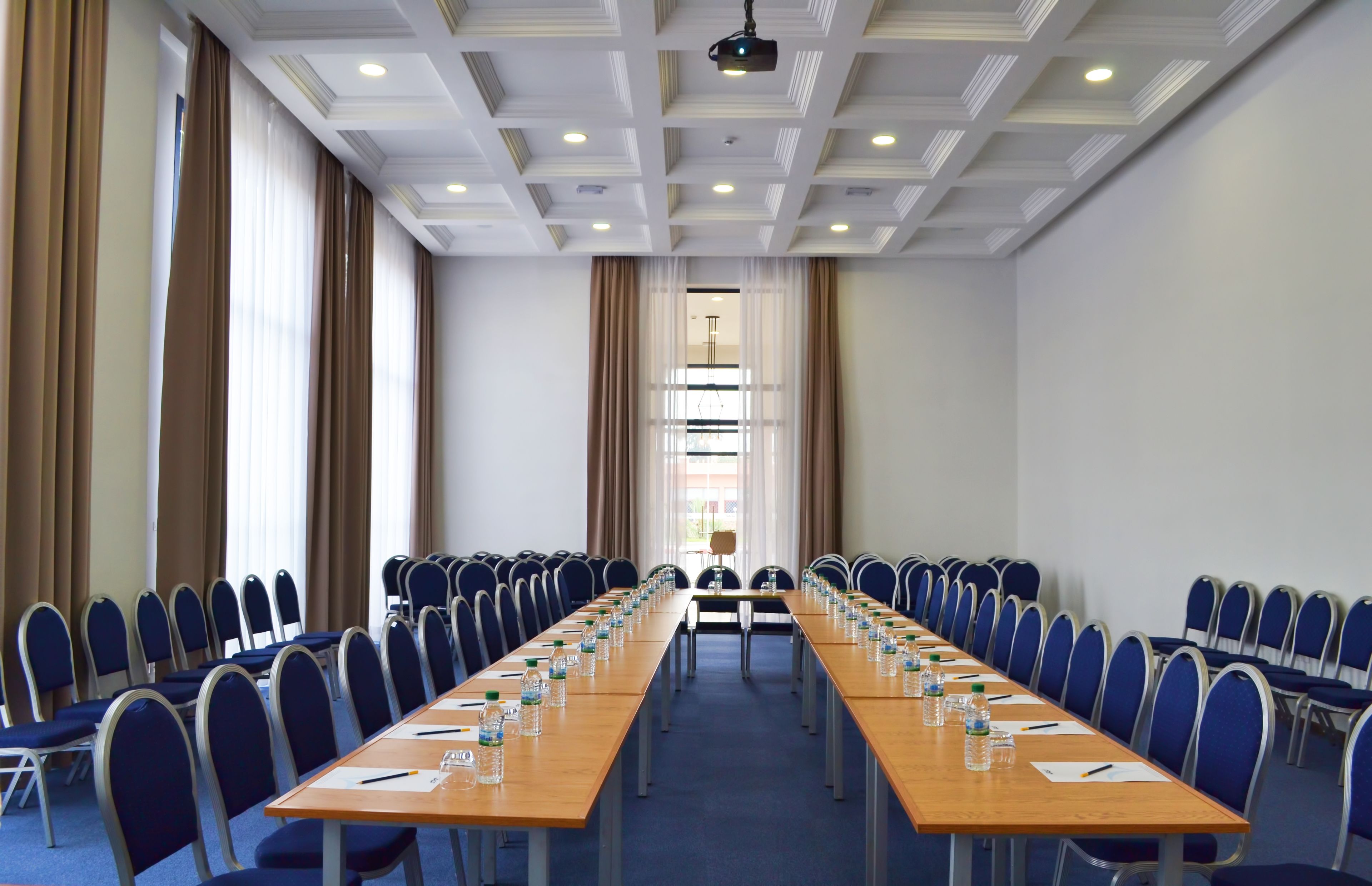 Une salle de conférence avec une longue table, des chaises et des bouteilles d’eau.