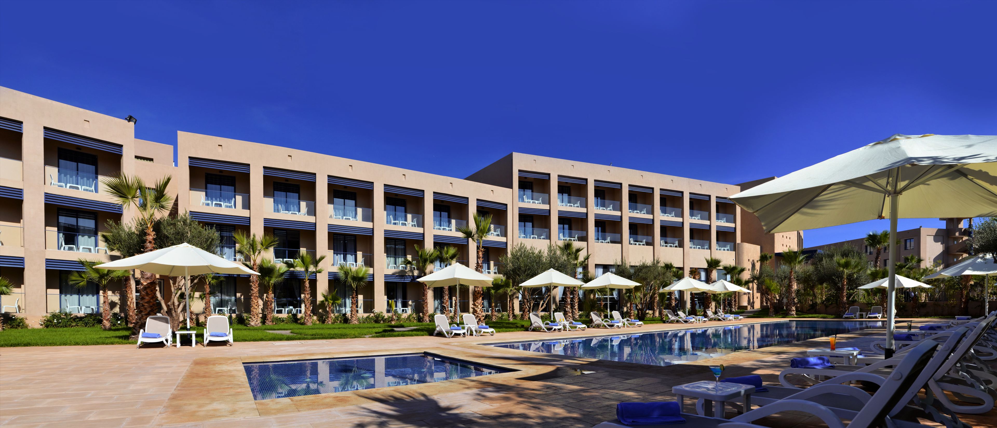 Un hôtel doté de nombreux balcons, d’un espace piscine extérieur et de chaises longues.