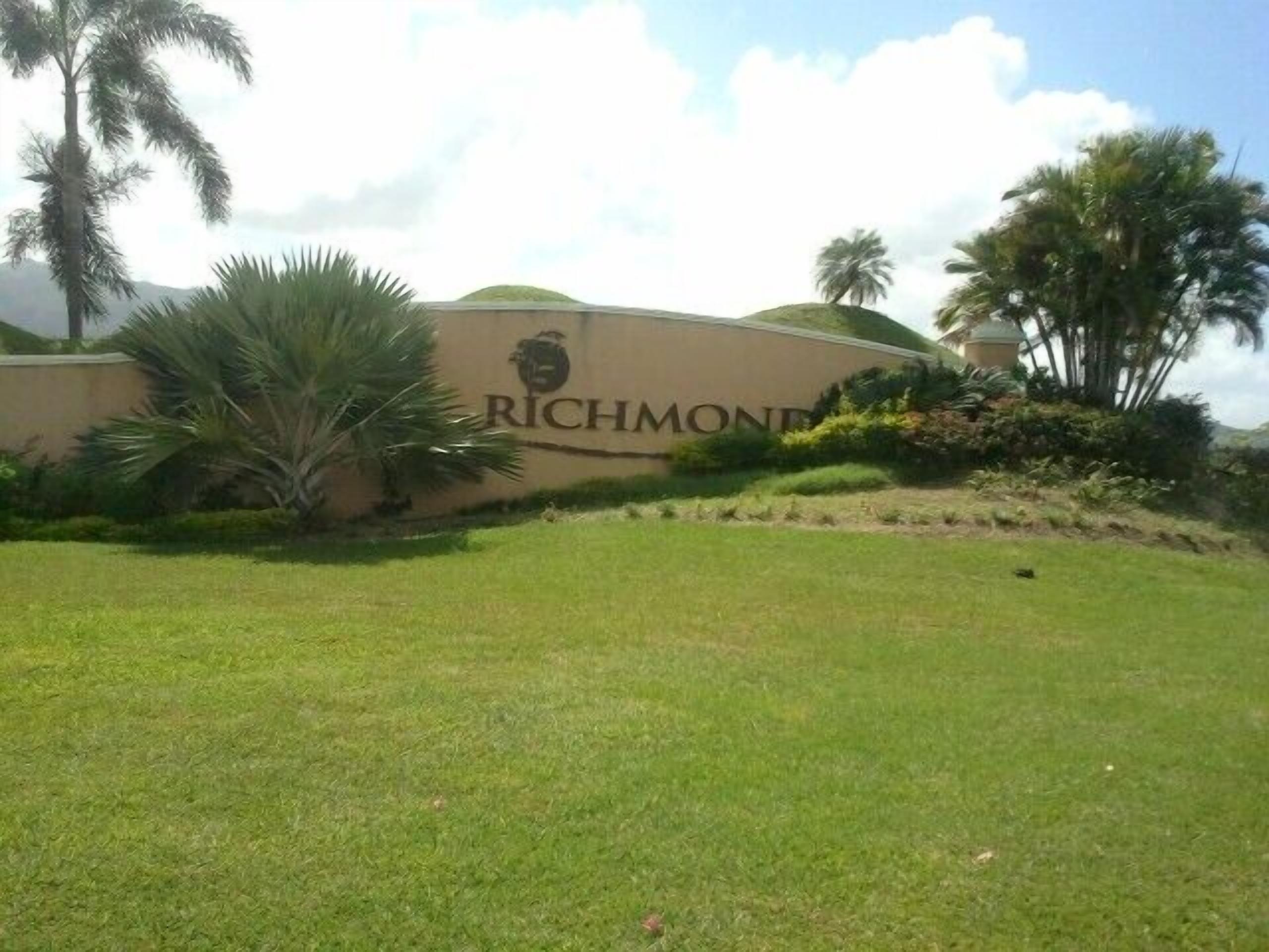 A sign with the word "RICHMOND" and a logo, surrounded by greenery and palm trees.