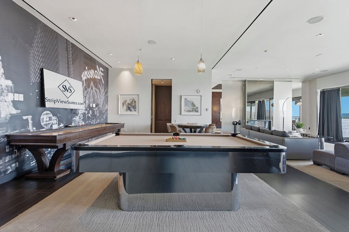 Un espace piscine moderne agrémenté d’une table de billard, d’œuvres d’art encadrées et d’une fresque représentant un paysage urbain.