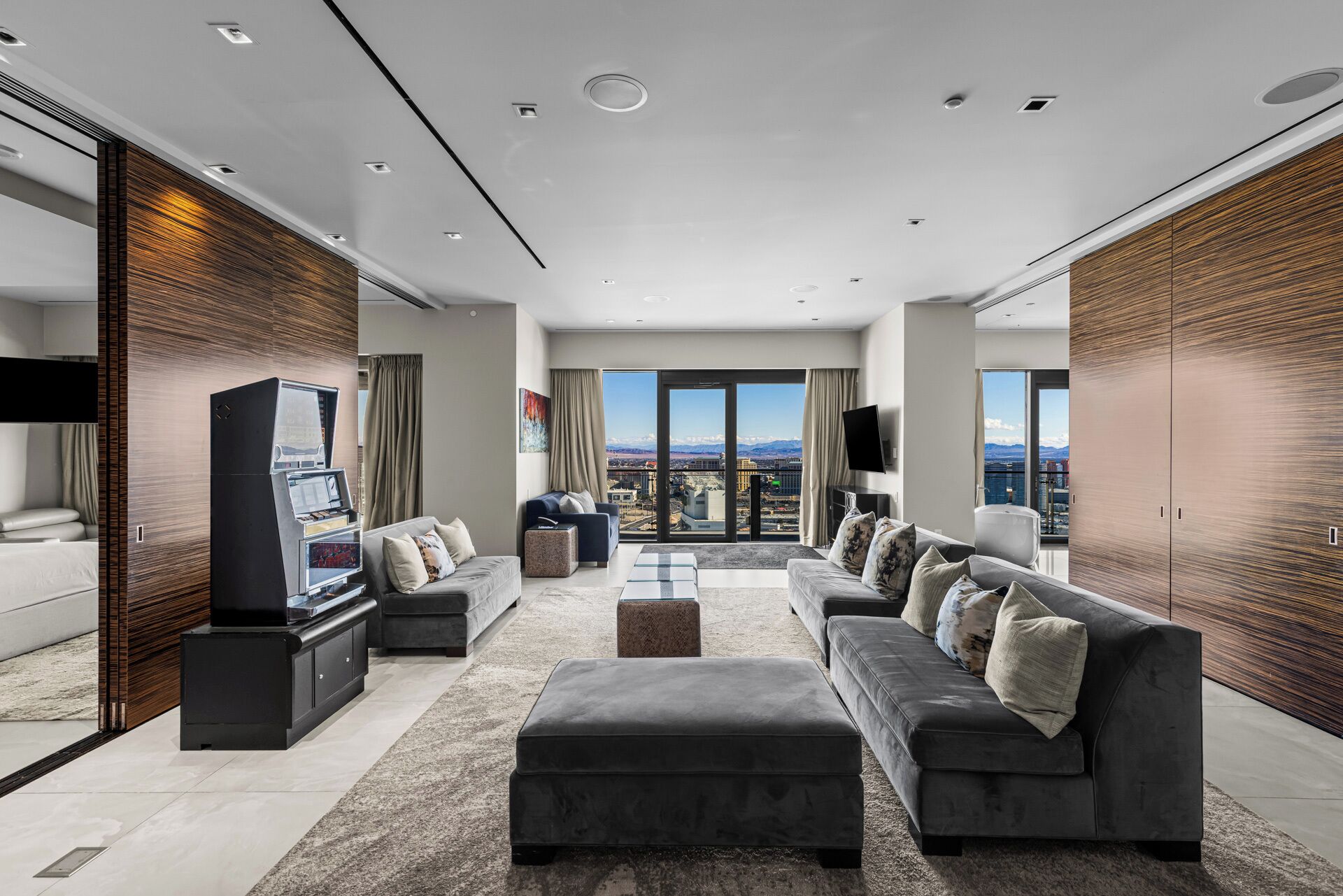 Een moderne woonkamer met een ruime modulaire bank, een flatscreen televisie en een stadszicht door ramen van vloer tot plafond.