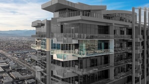 Un edificio de varios pisos con un diseño arquitectónico moderno, que cuenta con balcones y amplias ventanas.