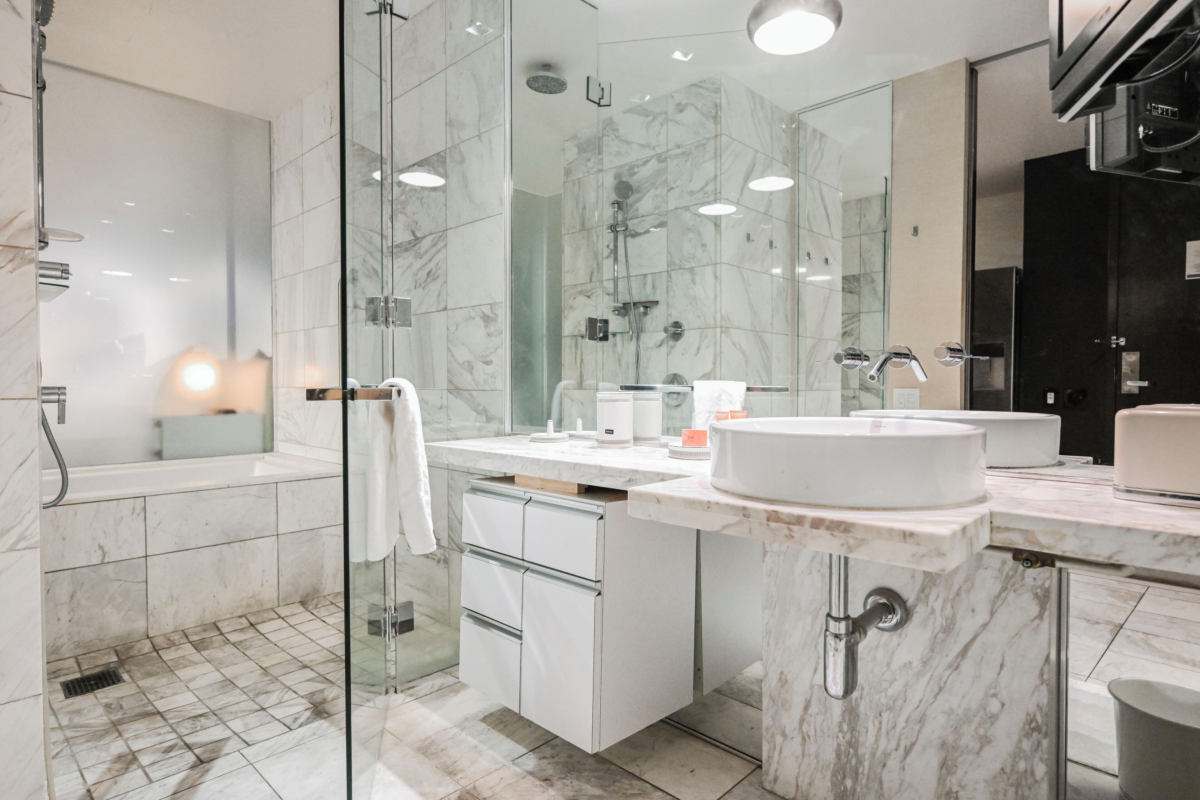 A modern bathroom with a glass shower enclosure, a white sink, and a large mirror.