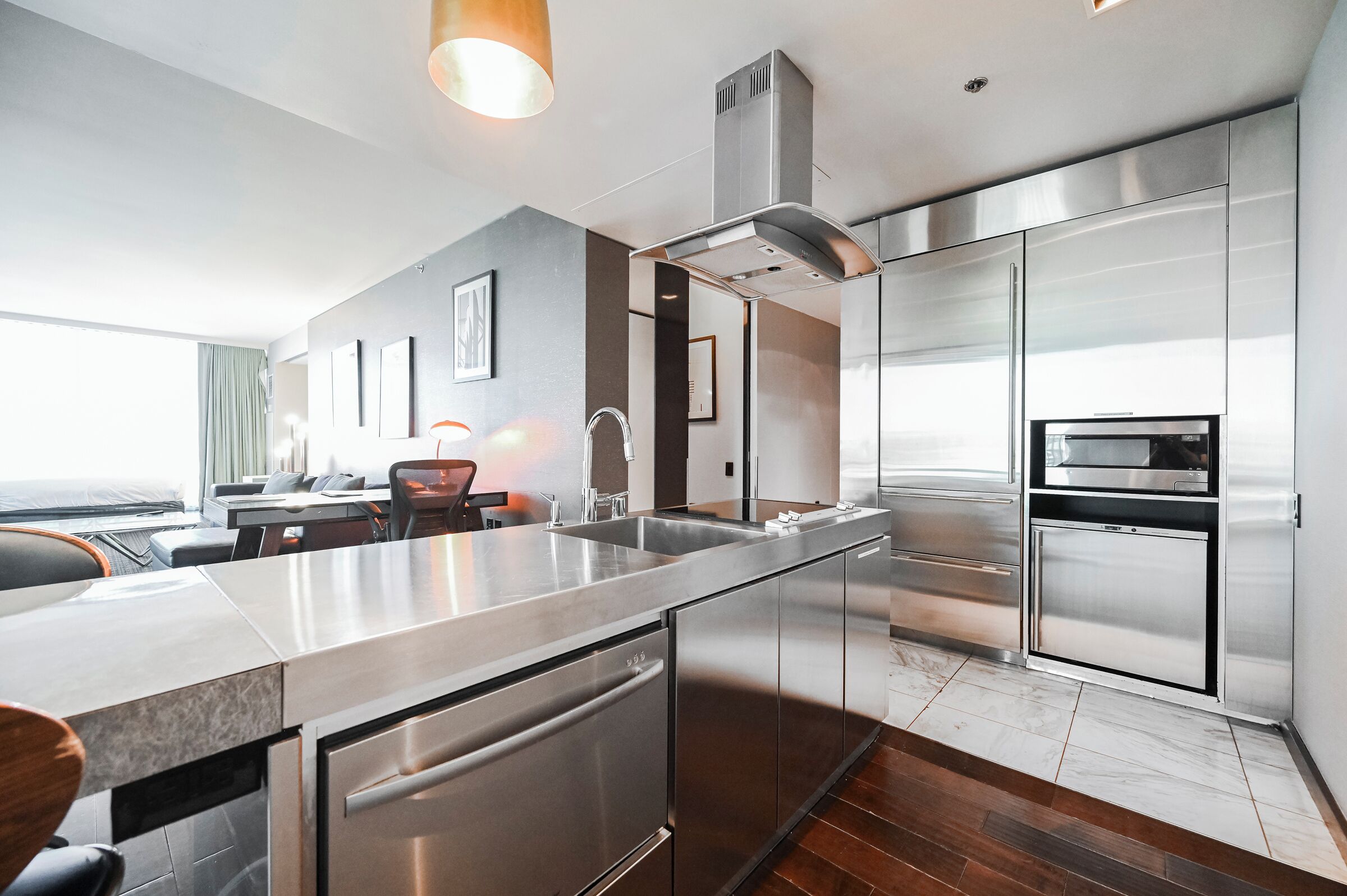A modern kitchen with stainless steel appliances, a large island, and a dining area with a view.